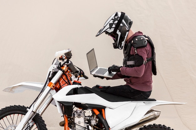 Motorradfahrer, der Laptop in der Wüste durchsucht
