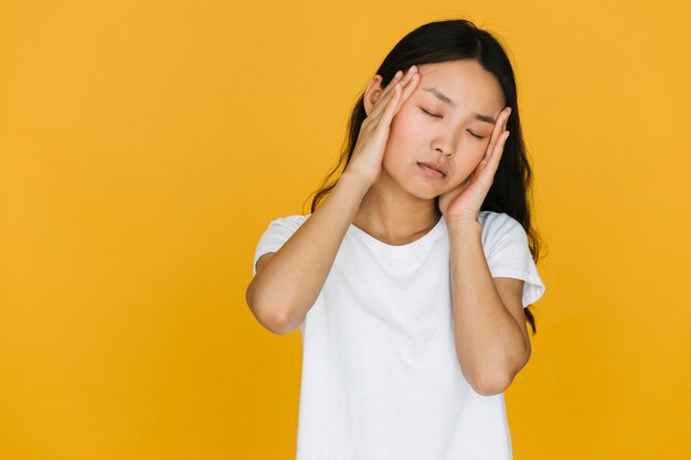 Müde asiatische Frau mit orange Hintergrund