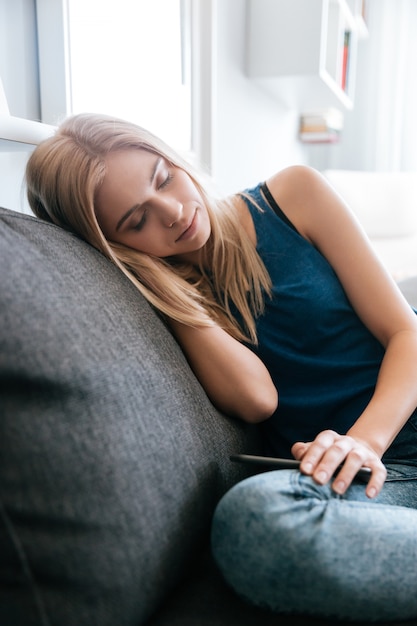 Müde erschöpfte junge Frau, die zu Hause auf dem Sofa schläft