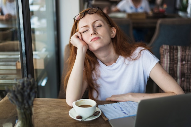 Müde Frau, die am Tisch sitzt