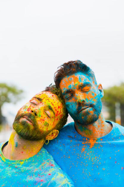 Müde Homosexuelle, die sich nach Holi-Feier aneinander lehnen