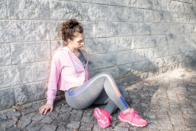 Kostenloses Foto müde sportlich attraktive mädchen sitzen auf pflaster