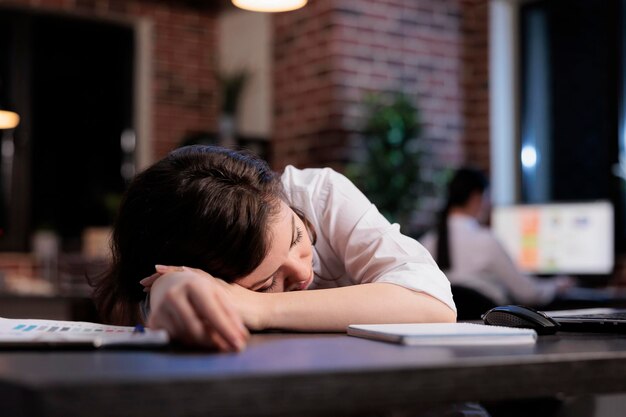 Müder Büroangestellter mit Burnout-Syndrom, der wegen extremer Müdigkeit bei der Arbeit schläft. Erschöpfter Geschäftsführer, der nach Überstunden unter Schläfrigkeit leidet.