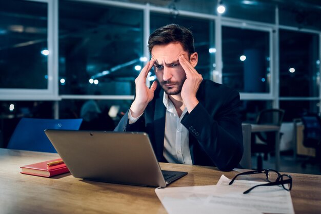 Müder Geschäftsmann, der nachts mit der Arbeit fertig ist