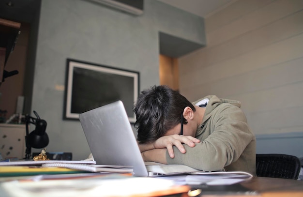 Müder Junge, der auf dem Computer sich lehnt