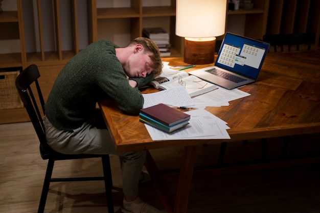 Müder junger Mann, der in einem virtuellen Klassenzimmer lernt