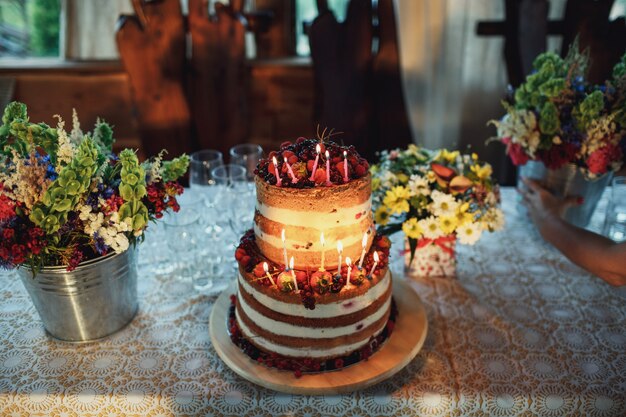 Müder Kuchen aus weisser Sahne und Beeren mit brennenden Kerzen