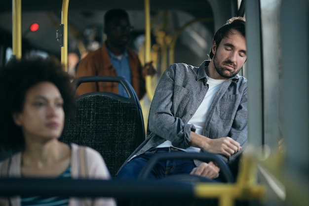 Müder Mann, der beim Pendeln mit dem Bus ein Nickerchen macht