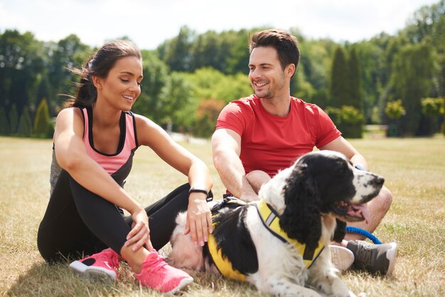 Müdes Paar und ihr Hund ruhen sich nach dem harten Training aus