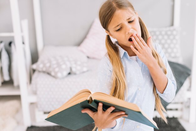 Müdes reizendes Mädchen, das ein Buch liest