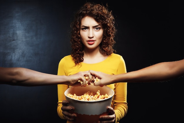 Mürrische frau hält popcorn-eimer und will nicht teilen