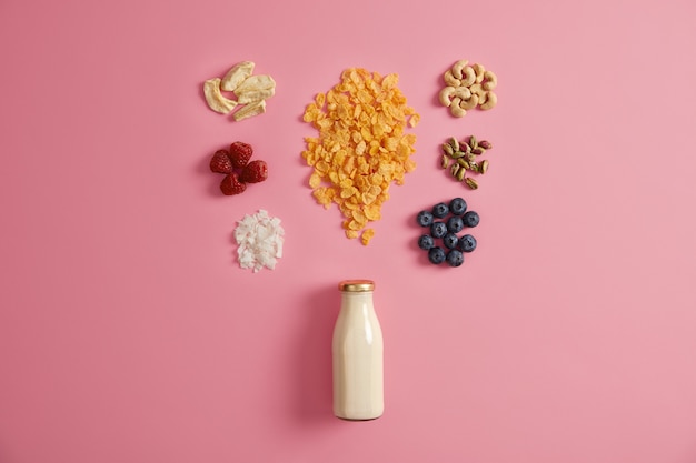 Müsli mit getrockneten Äpfeln, Datteln, Cashewnüssen, Pistazien um die Flasche mit Milch