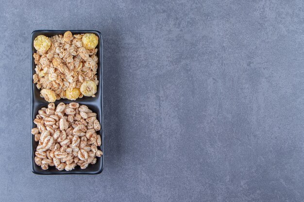 Müsli und Cornflakes in Schalen, auf dem Marmorhintergrund. Foto in hoher Qualität