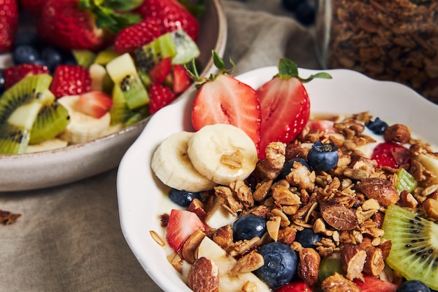 Müslischalen mit Joghurt, Früchten und Beeren auf weißer Oberfläche