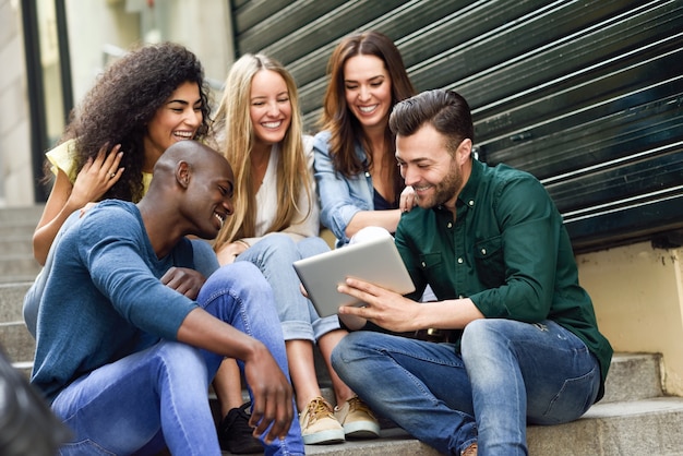 Multi-ethnischen Gruppe von jungen Menschen Blick auf einen Tablet-Computer