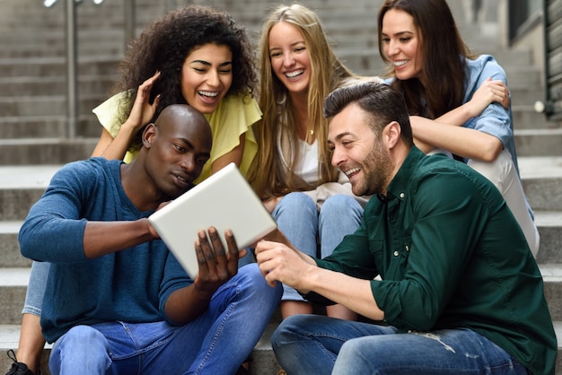 Multi-ethnischen Gruppe von jungen Menschen Blick auf einen Tablet-Computer