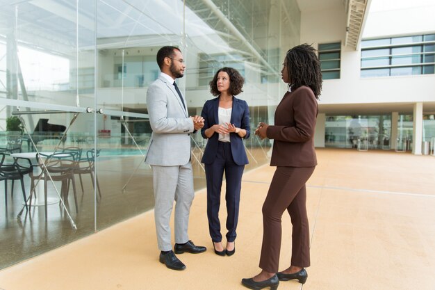 Multiethnisches Team, das Projekt nahe Bürogebäude bespricht