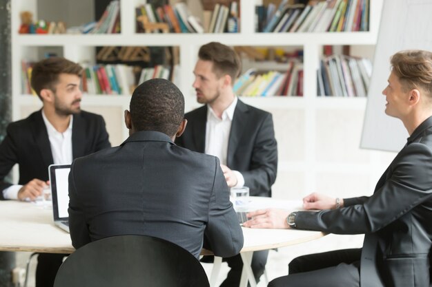 Multiethnisches Team von männlichen Mitarbeitern, die Unternehmenspläne während des Briefings besprechen.