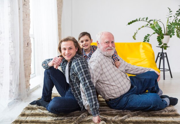 Multigenerationale Männer, die zu Hause auf Teppich sitzen