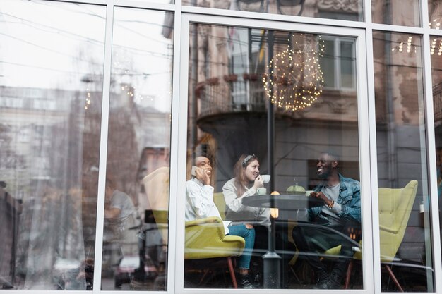 Multikulturelle Freunde, die nahe Fenster sitzen