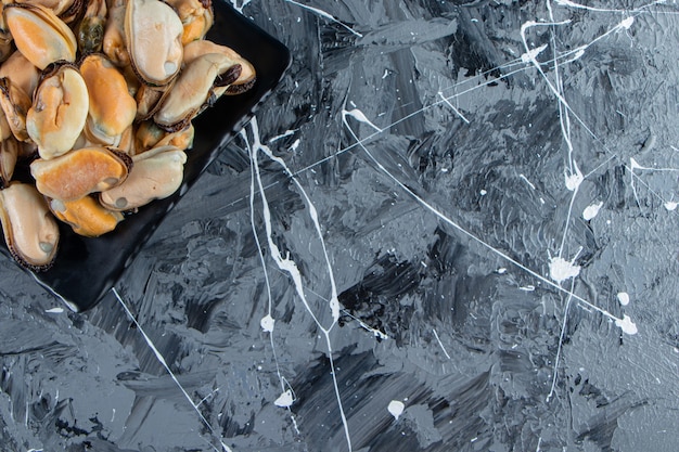 Muscheln ohne Schale auf einer Platte auf dem Marmorhintergrund.