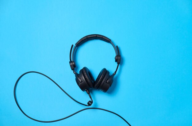 Musik- oder Podcast-Hintergrund mit Kopfhörern auf blauem Tisch flach liegend Draufsicht flach liegend Platz für Text