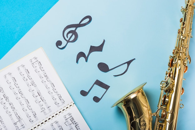 Musikalisches Notizbuch und goldene Saxophones auf blauem Hintergrund