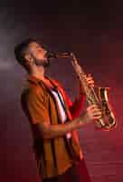 Kostenloses Foto musiker, der das saxophon im nebel spielt
