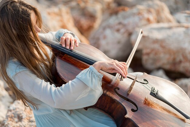 Musiker spielt Cello auf Felsen