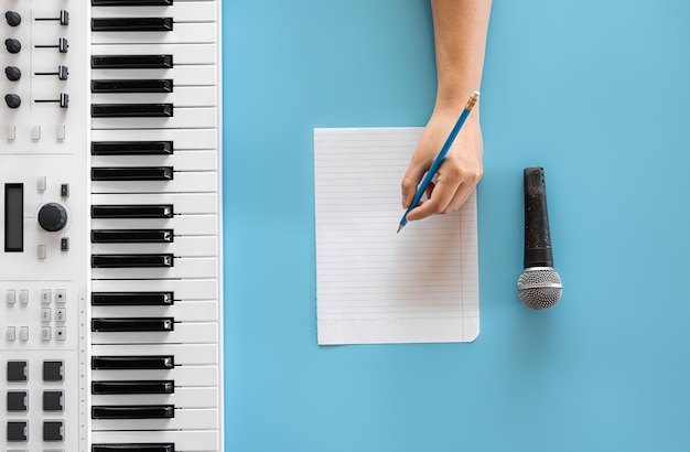 Musiktasten, leeres papier und mikrofon auf blauem hintergrund, musikschriftkonzept, musikalische kreativität, flache lage.