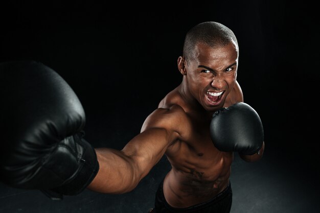 Muskulöser afroamerikanischer Mannkastenkämpfer, der Tritte übt