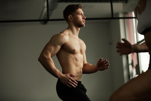 Kostenloses Foto muskulöser athlet wärmt sich auf, während er in einem fitnessstudio trainiert