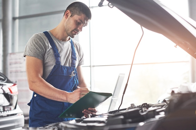 muskulöser Autoservice-Arbeiter, der Fahrzeug repariert.