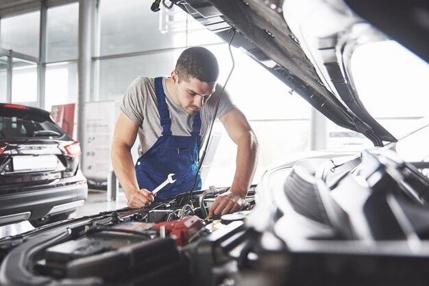 muskulöser Autoservice-Arbeiter, der Fahrzeug repariert.