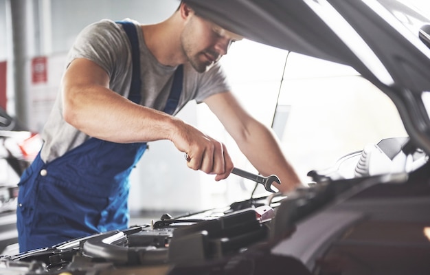 muskulöser Autoservice-Arbeiter, der Fahrzeug repariert.