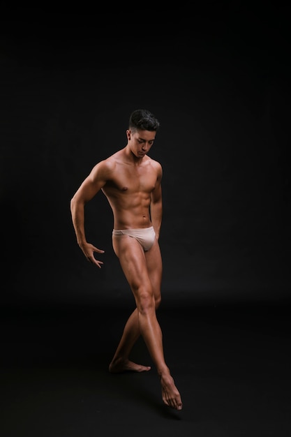 Muskulöser Balletttänzer, der würdevoll Bein ausdehnt