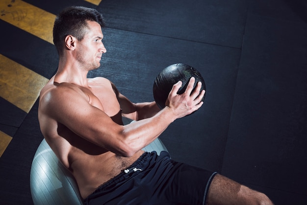 Muskulöser junger Mann, der mit Medizinball trainiert