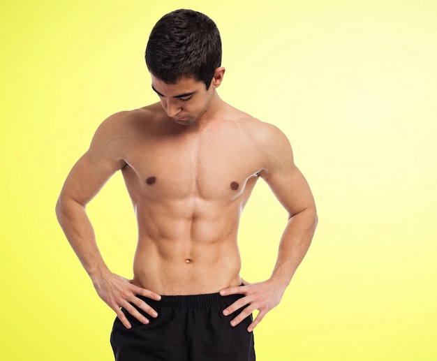 Muskulöser Mann ohne Hemd mit gelbem Hintergrund