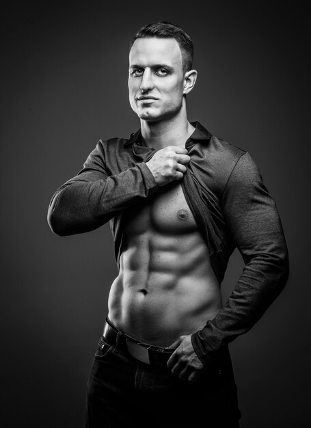Muskulöser Typ posiert mit Bauchmuskeln und muskulösem Körper