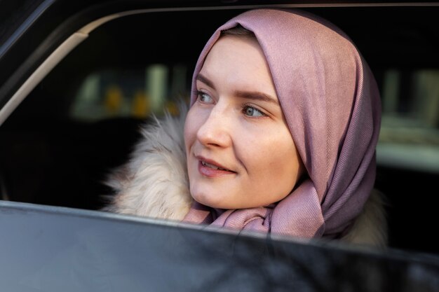 Muslimische Frau mit Hijab, die im Urlaub die Stadt mit einem Auto erkundet