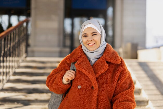 Muslimische Frau mit Hijab verlässt das Hotel und lächelt im Urlaub