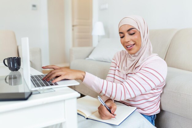 Muslimische junge Frauen tragen Hijab, indem sie die Kundenadresse auf dem Computer-Laptop zu Hause morgens eingeben und überprüfen. Konzeptgeschäft klein und online einkaufen