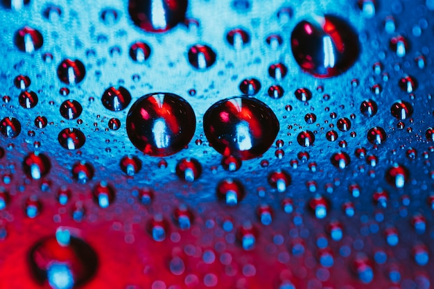 Muster des Wassertröpfchens auf rotem und blauem Oberflächenhintergrund