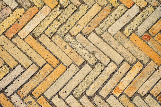 Muster mit rechteckigen gelben Ziegelfliesen in Form eines Fischgrätenmusters. Diagonale Textur. Abstrakter Hintergrund aus alten Ziegeln, Keramik, Kopfsteinpflaster, Draufsicht. Idee für eine einfache Schreibtischtapete
