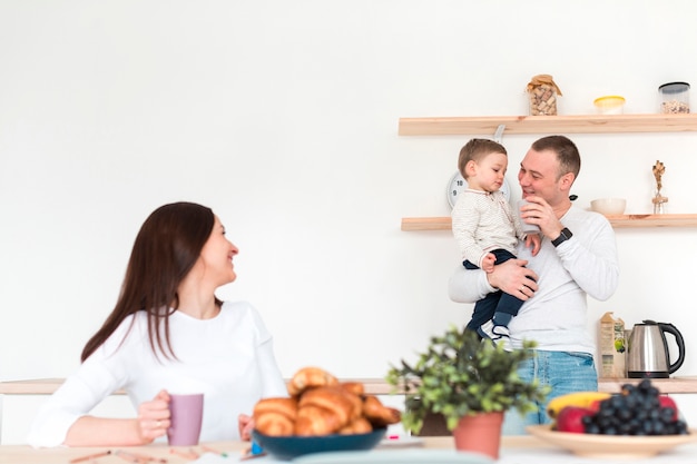 Mutter beobachtet Vater, der Kind in der Küche hält