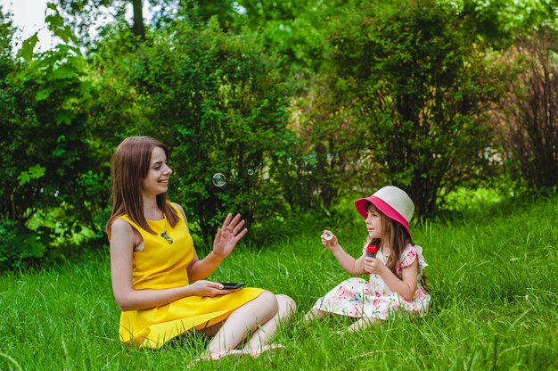 Mutter beobachtete, wie ihre Tochter bläst Seifenblasen