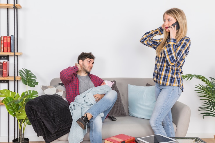 Kostenlose Foto mutter, die am telefon nahe vater mit baby spricht