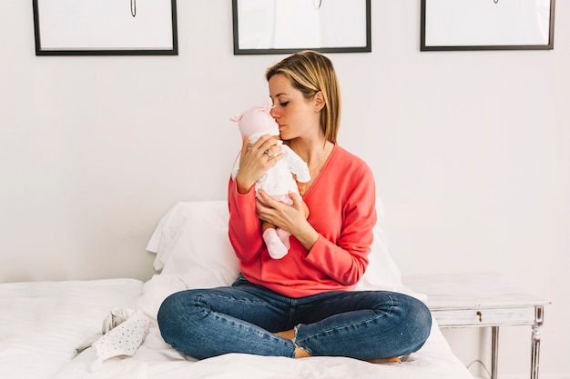 Mutter, die Baby im Schlafzimmer küsst