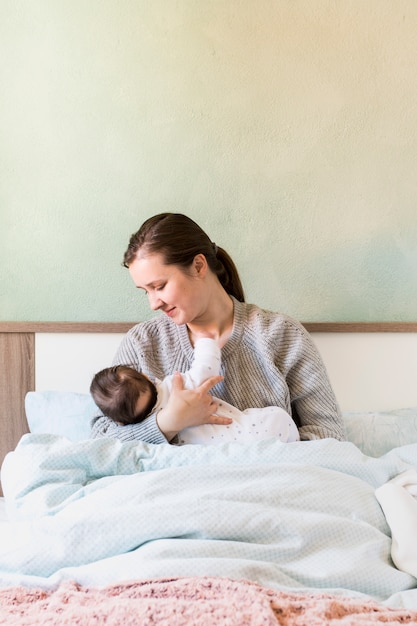 Kostenloses Foto mutter, die baby in den armen im bett hält