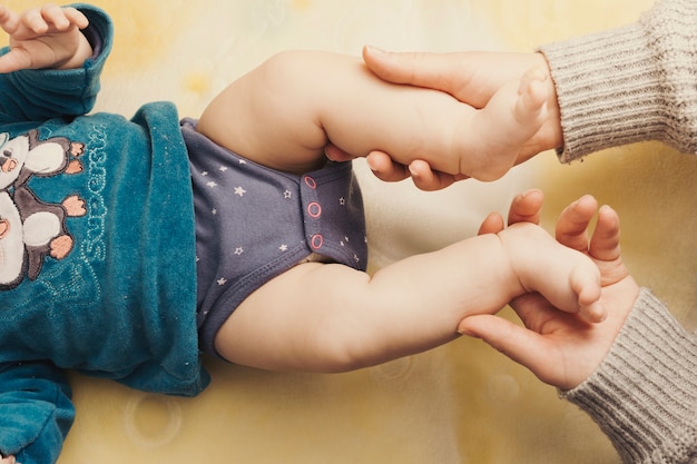 Mutter, die beine des schätzchens auf bett anhält